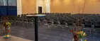 Konferencelokale med stole stillet op på rækker og et podie med en talerstol