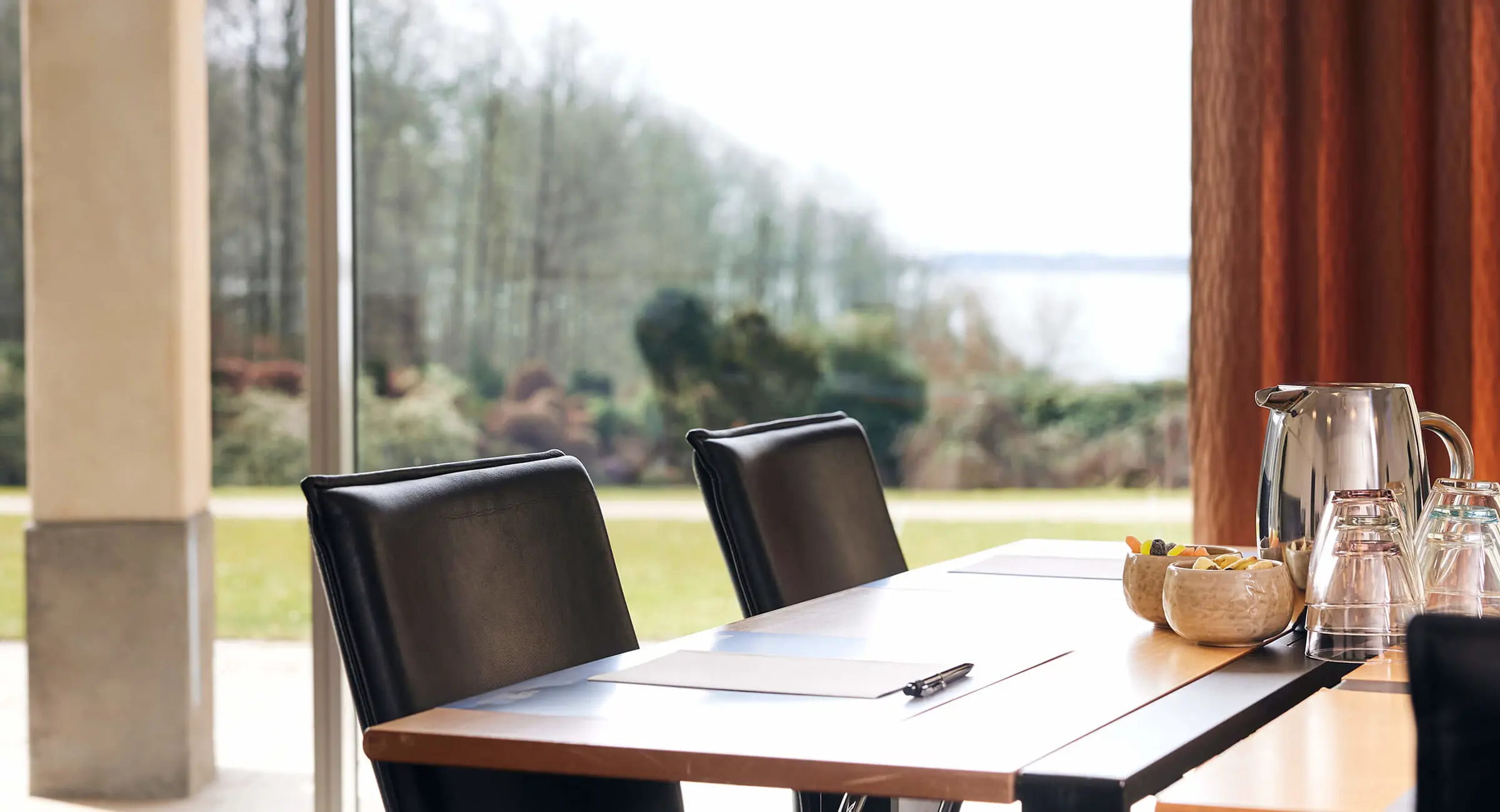 Et konferencelokale med udsigt til en park og Vejle Fjord