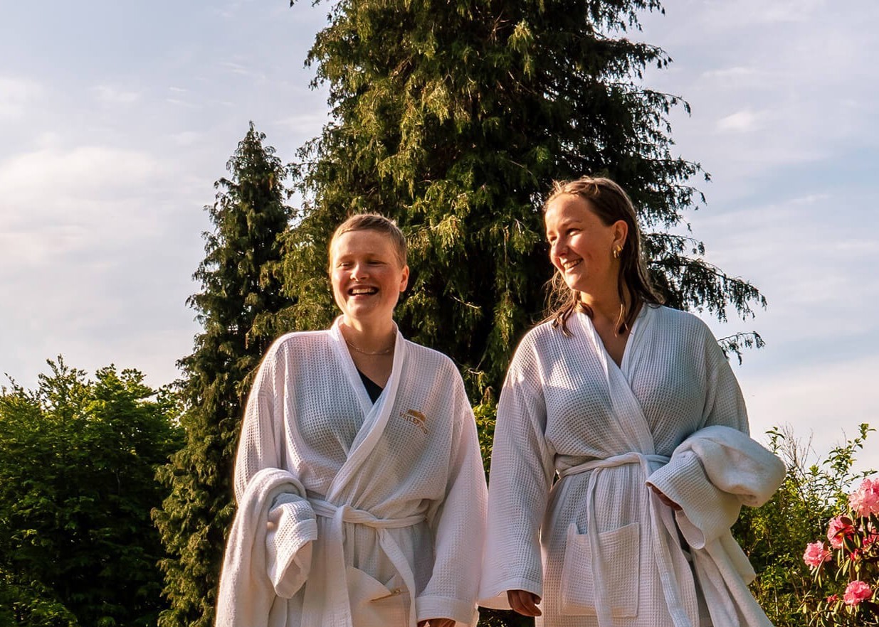 Et par i badkåber slapper af i liggestole i en spa omgivet af natur