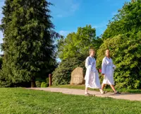 Kvinder i badekåber går på en sti i en park med en mindesten for Vejlefjords grundlæggelse
