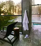 To mennesker nyder roen og varmen i badekåber foran en pejs i et spaområde