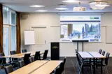 Krystalsalen mødelokale opstillet i skoleborde mod tavle og lærred