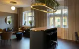Hyggeligt rum med lange lyse gardiner og bløde møbler, samt en bar i midten