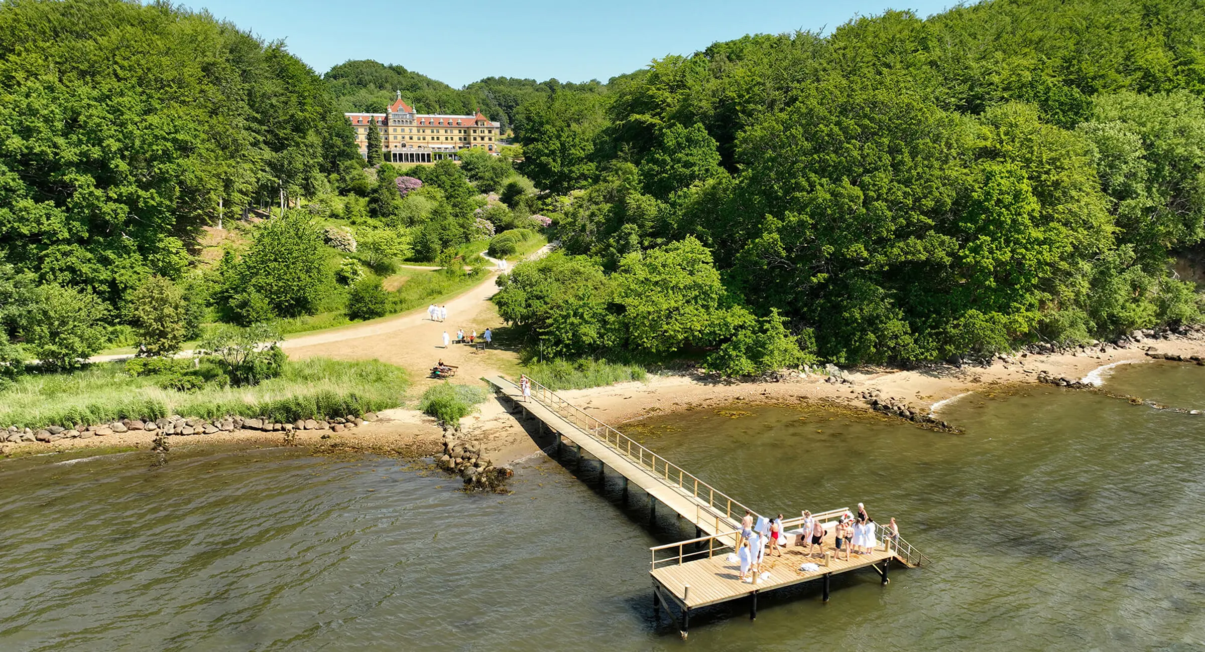Dronebillede af Hotel Vejlefjord set fra fjorden og op gennem parken