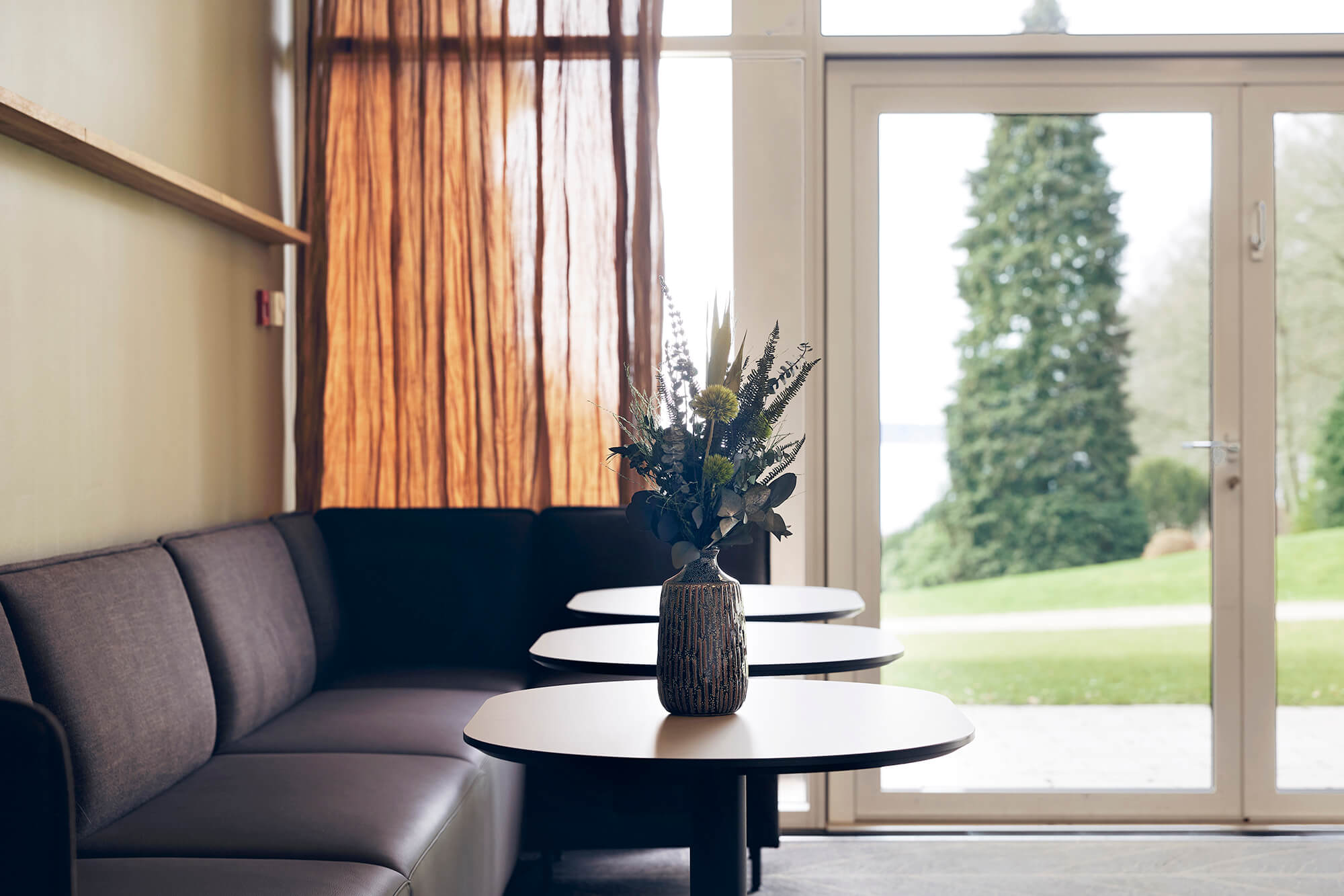 En stor loungesofa med udsigt til en park og træer