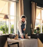 Tjener der dækker op i restauranten på Hotel Vejlefjord
