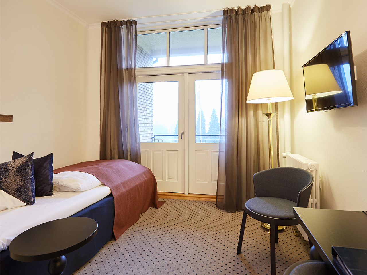 Hotelværelse med enkeltseng og dør til balkon