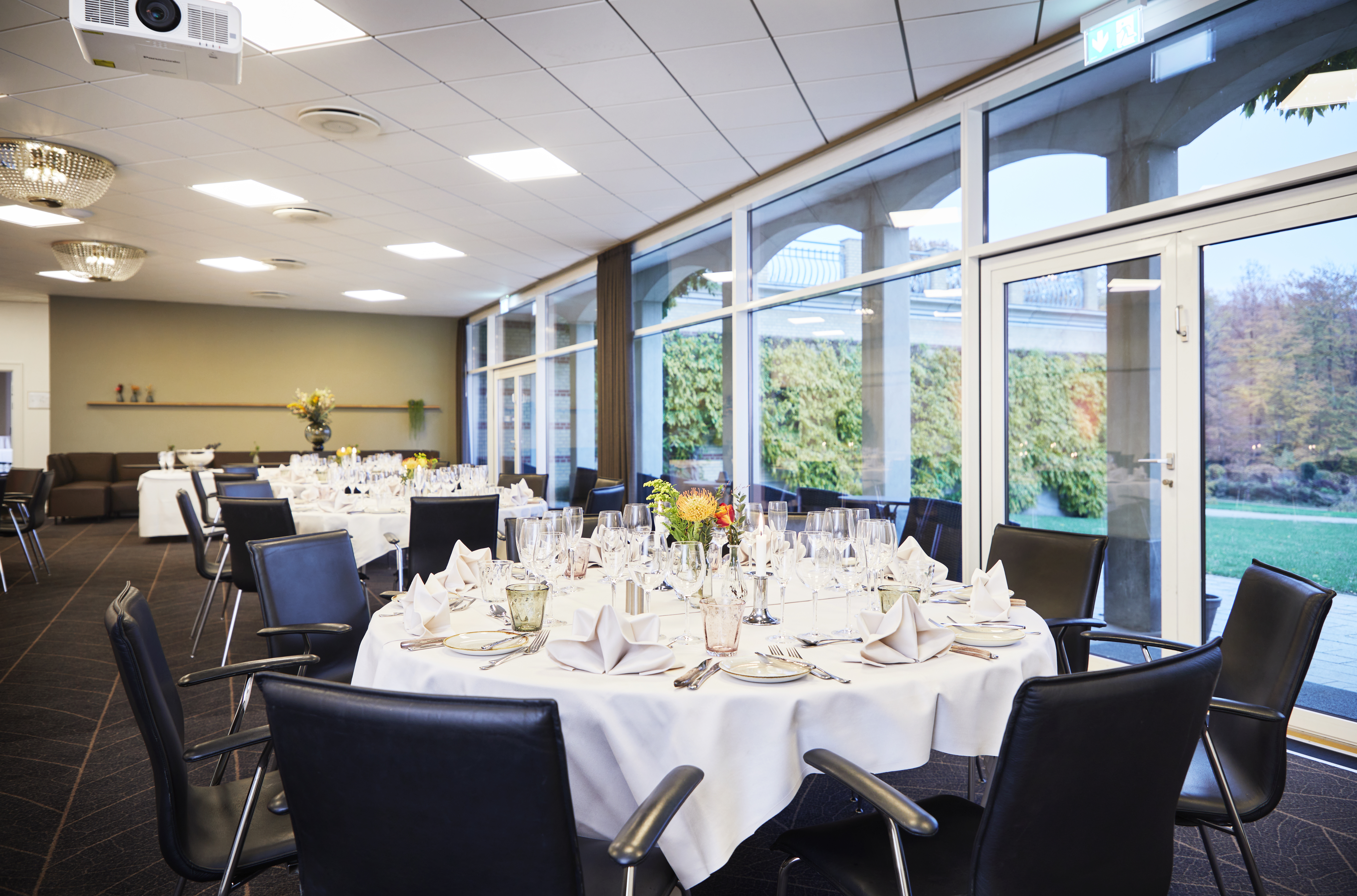 Runde bord dækket op til fest med panoramavinduer til parken