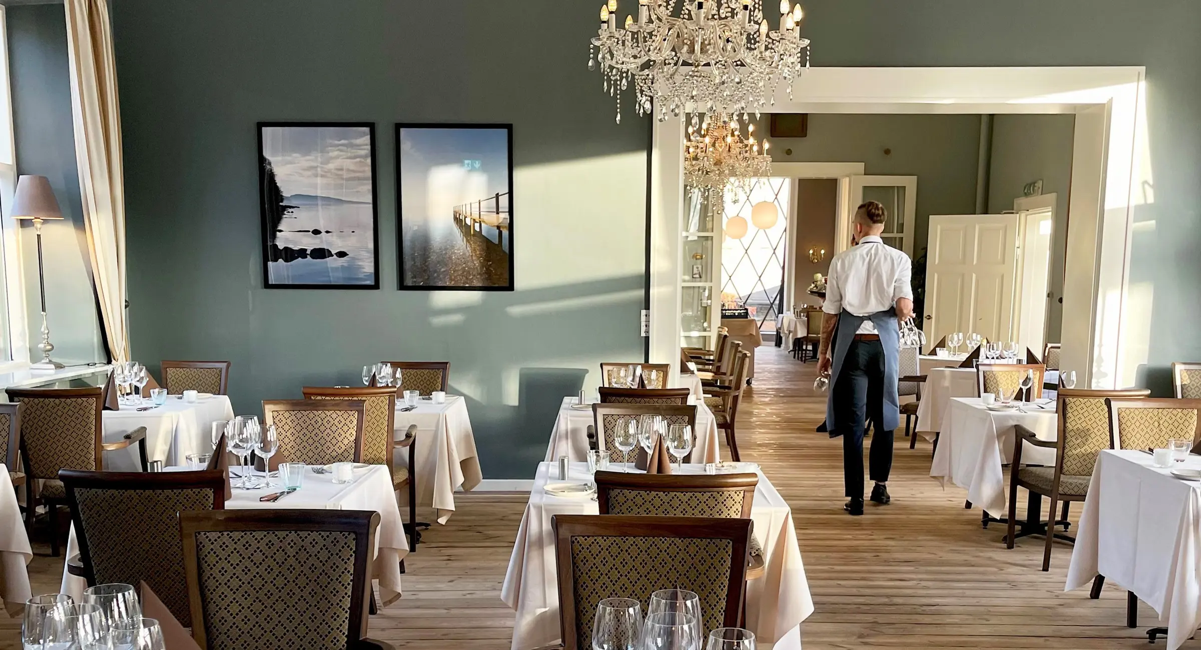 Et bord i en restaurant dækket op til middag, hvor to stole kigger ud på en parks flotte udsigt