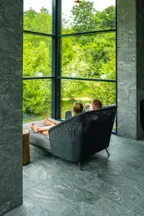 Et par sidder i en loungestol foran et stort vindue der inviterer naturen indenfor i spa