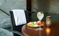 Et cafebord dækket op med en drink og frugt i en spa med bassin i baggrunden