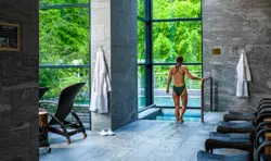 Kvinde er på vej ned i en pool i et spaområde med liggestole