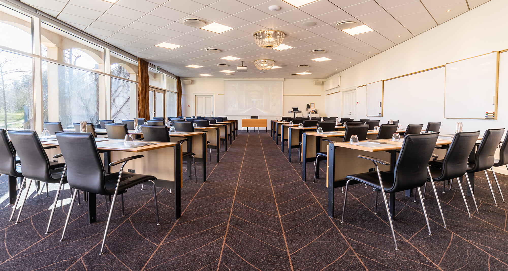 Mødelokale med flotte krystallamper opstillet med borde i sildeben 