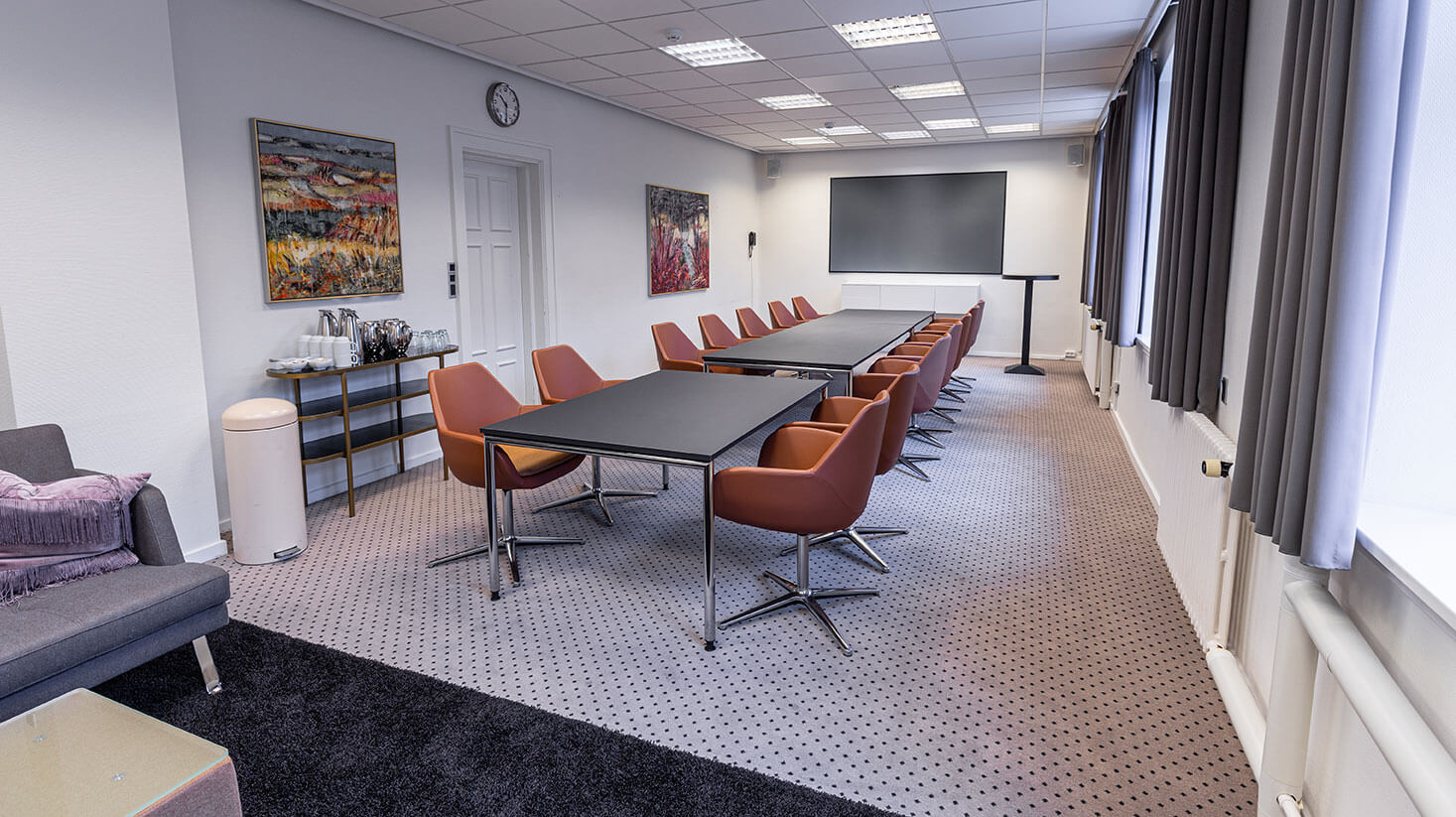 Mødelokale med langbord og stole til 14 personer, samt stor skærm 