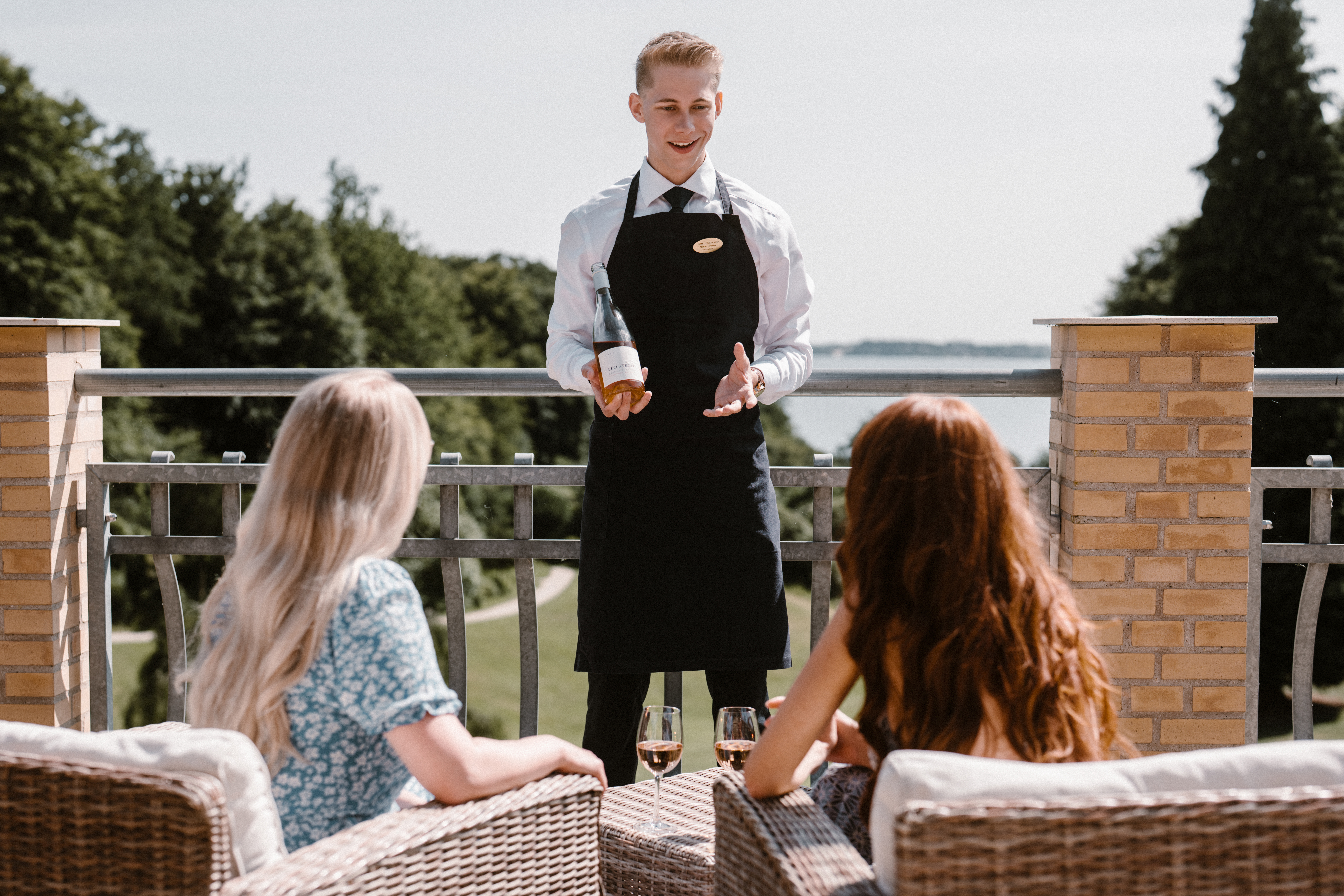 Et bord i en restaurant dækket op til middag, hvor to stole kigger ud på en parks flotte udsigt