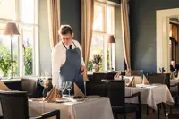En tjener dækker borde i en hyggelig restaurant