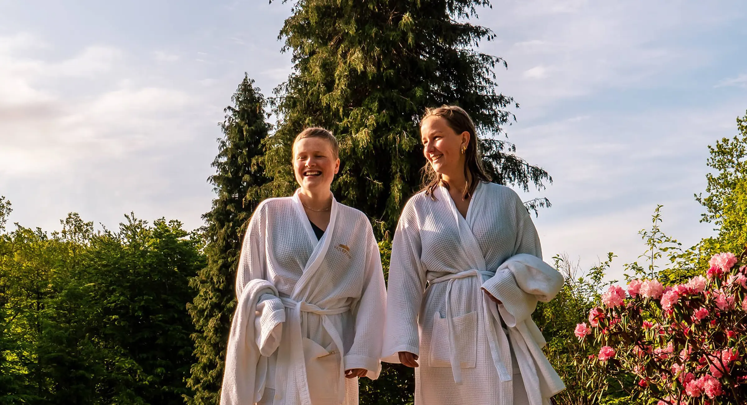 Et par i badkåber slapper af i liggestole i en spa omgivet af natur