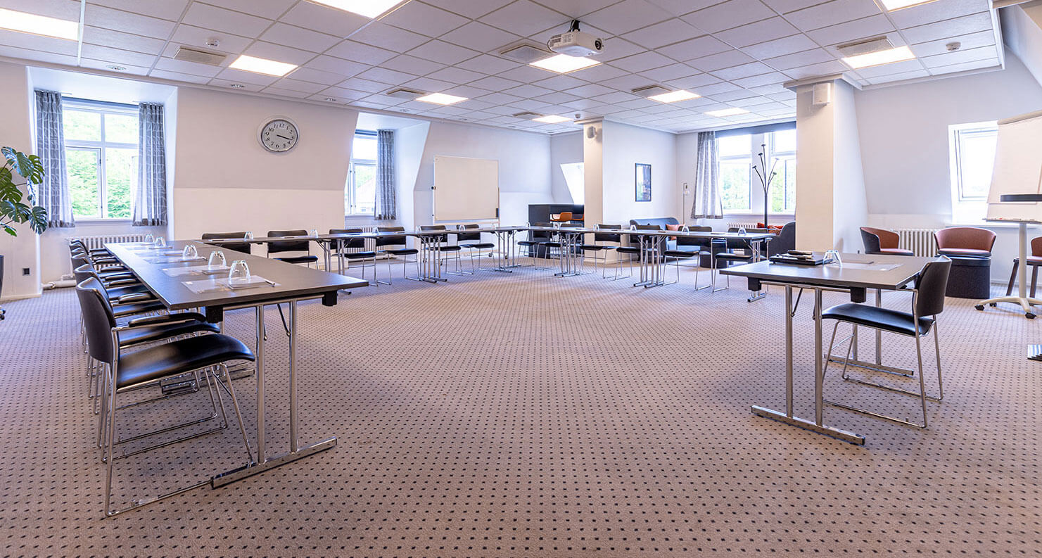 Lyst og rummeligt mødelokale opstillet i u-bord