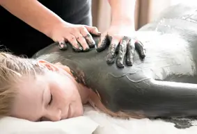Hænder der masserer ler ind på overkroppen af en kvinde