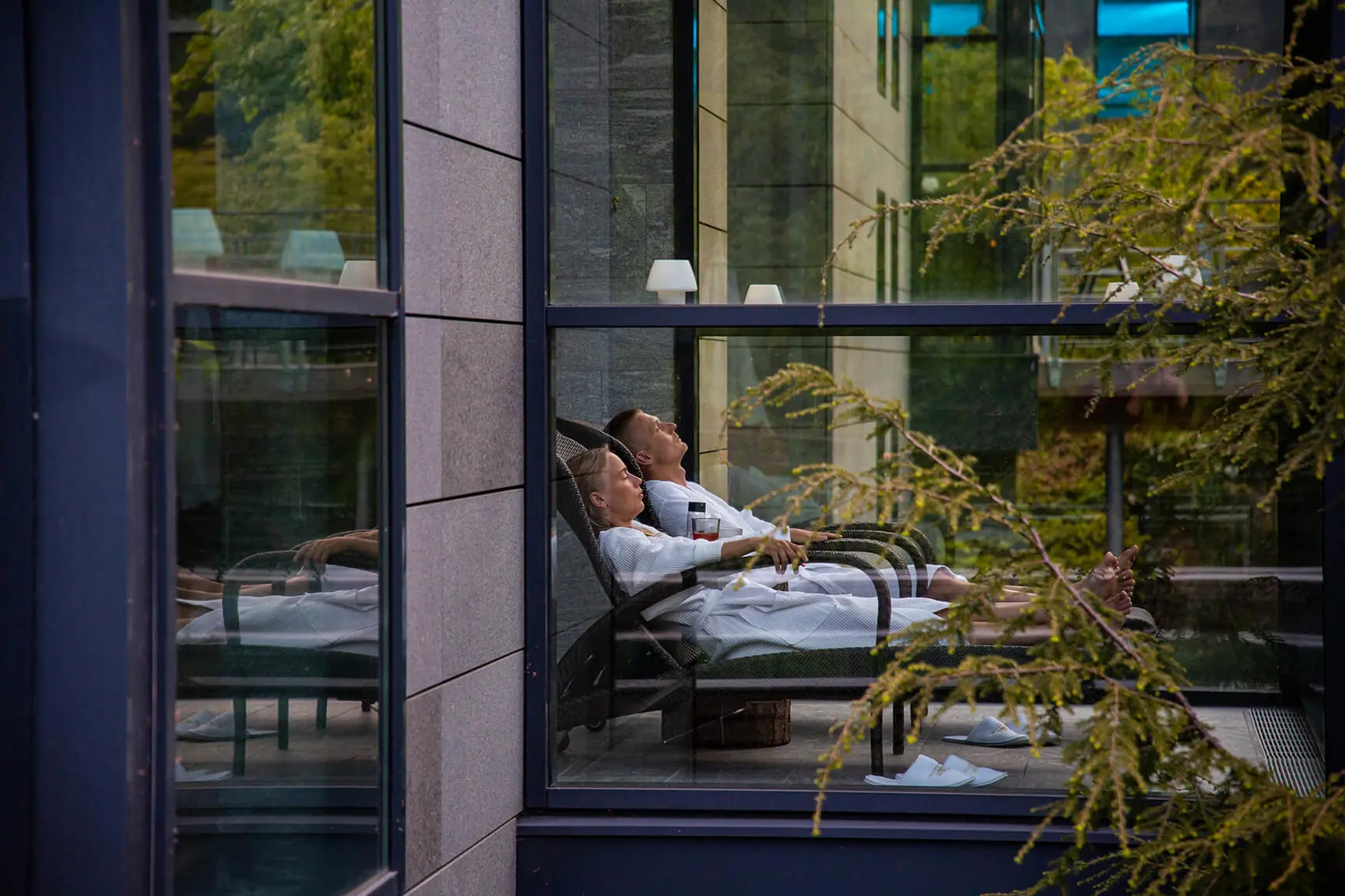 En udendørspool med to personer, der svømmer under en lyserød aftenhimmel