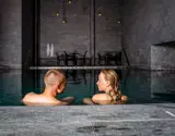Et par der kigger på hinanden mens de sidder i et stort bassin