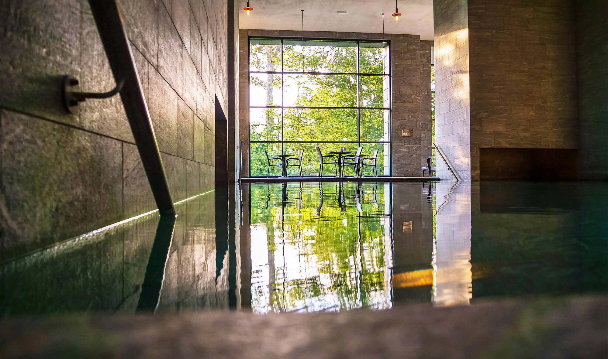 Et smukt stort termisk bad med lysindfal og grønt uden for de store vinduer