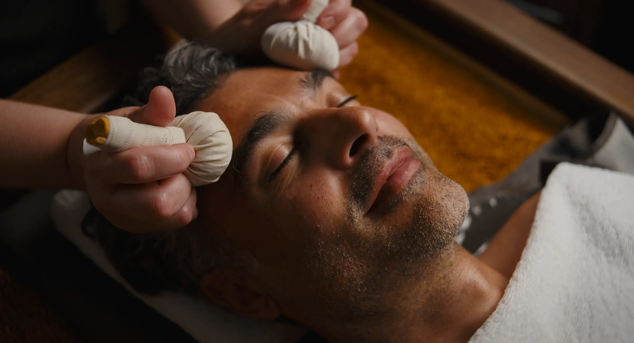 En kvinde får en massage behandling af en terapeut i et hyggeligt rum med levende lys