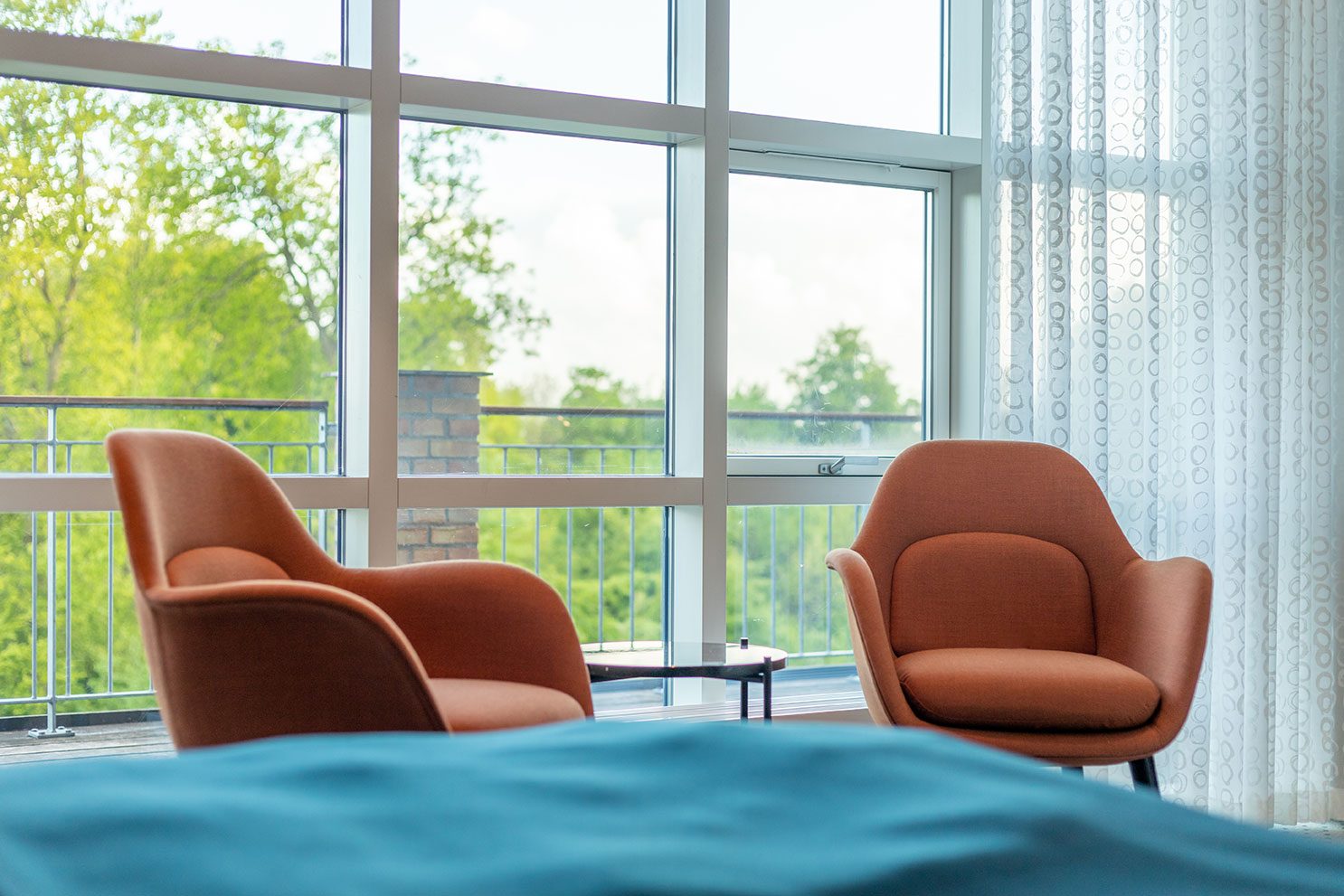 To cognacfarvede lænestole på et hotelværelse med udsigt til skov