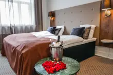 Et hotelværelse hvor der foran sengen står et bord med vinkøler og rosenblade