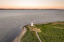 Dronefoto af et lille fyrtårn ved Vejle Fjord med smuk lyserød himmel