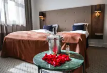 Et hotelværelse hvor der foran sengen står et bord med vinkøler og rosenblade