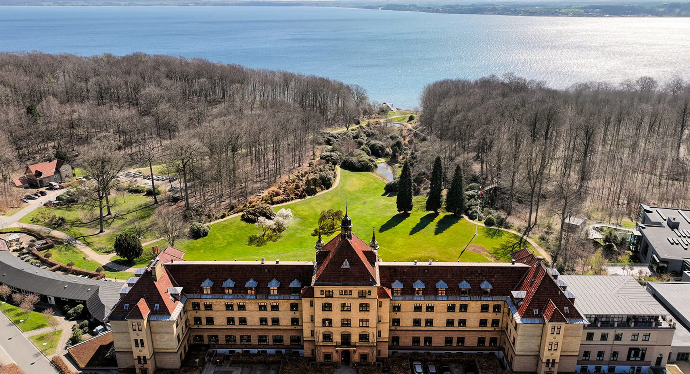 Drone billede af Hotel Vejlefjord, parken og fjorden på en forårsdag med solskin