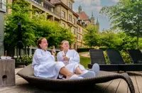 To kvinder på en stor solstol med Hotel Vejlefjords smukke bygning i baggrunden